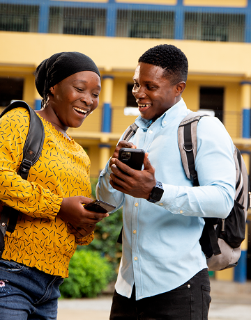 Women in yellow dress and Man in light blue shirt looking at phone and smiling